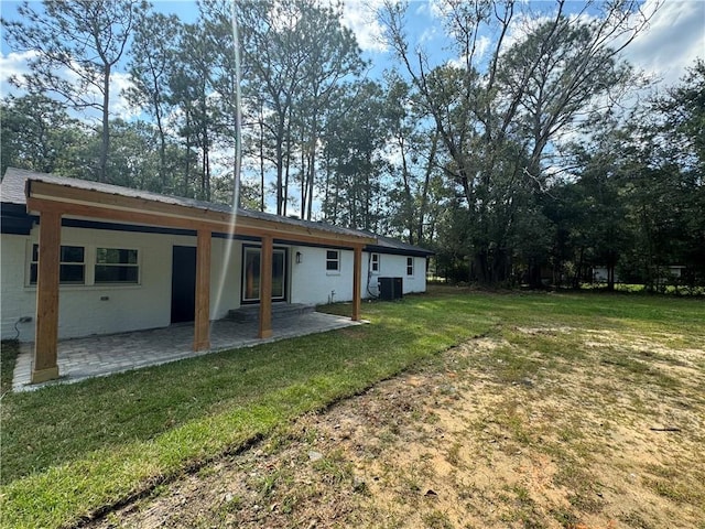 back of property featuring central AC unit, a lawn, and a patio area