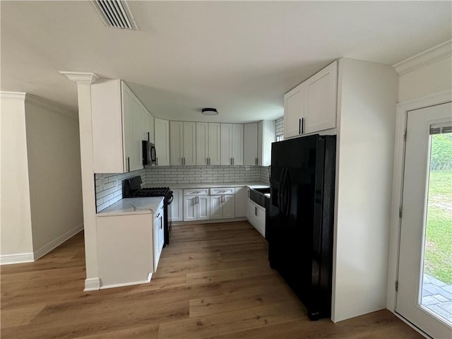 kitchen with backsplash, white cabinets, black appliances, and light wood-type flooring