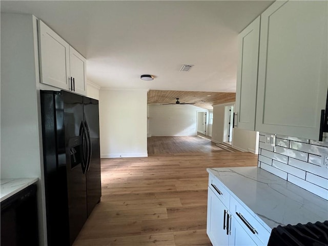 kitchen with black fridge, light stone countertops, light wood-type flooring, and white cabinets