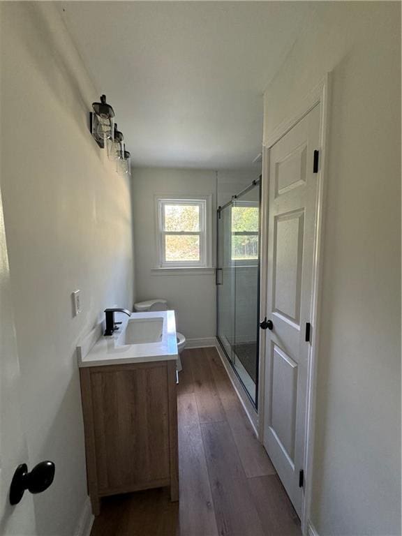 bathroom featuring toilet, vanity, an enclosed shower, and wood-type flooring