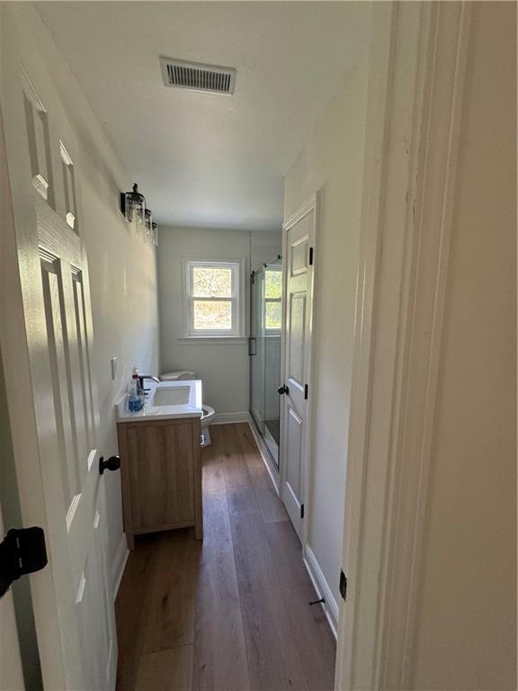 bathroom with hardwood / wood-style flooring, an enclosed shower, vanity, and toilet