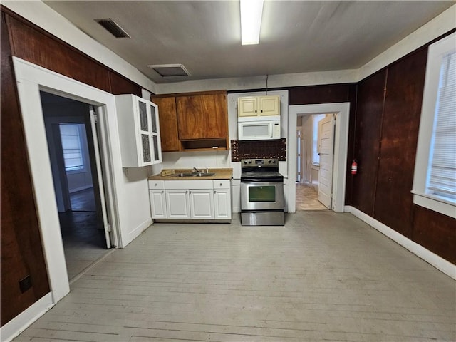 kitchen featuring backsplash, stainless steel range with electric cooktop, sink, light hardwood / wood-style flooring, and white cabinetry