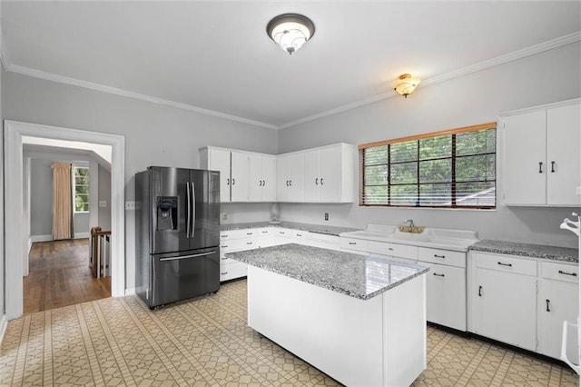 2007 Levert Dr N, Mobile, AL 36607 - kitchen featuring black fridge, ornamental molding, white cabinetry, a kitchen island, and light stone countertops