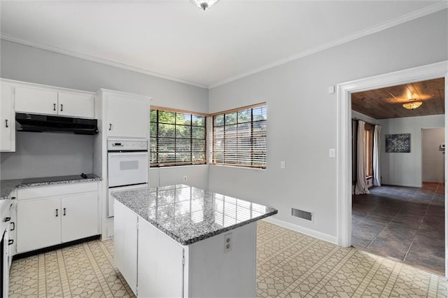 2007 Levert Dr N, Mobile, AL 36607 - kitchen with under cabinet range hood, double oven, a kitchen island, black electric stovetop, and white cabinets