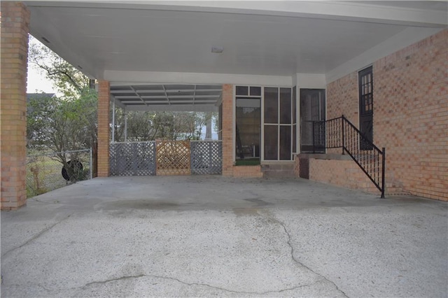 view of patio featuring driveway, fence, and a carport