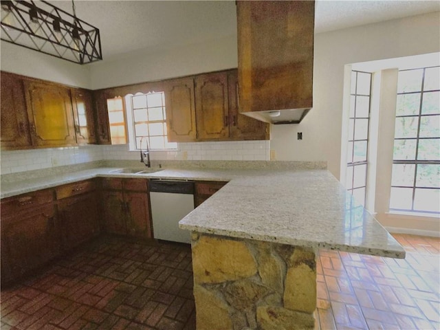 kitchen with dishwashing machine, a peninsula, a sink, light countertops, and decorative backsplash