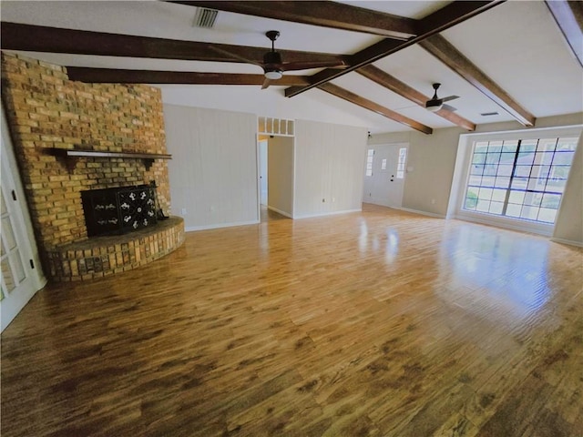 unfurnished living room featuring vaulted ceiling with beams, a fireplace, visible vents, ceiling fan, and wood finished floors