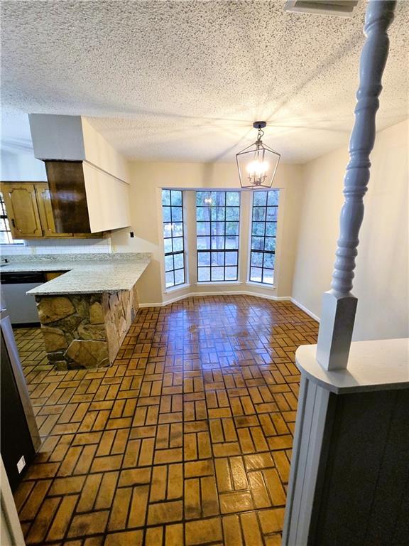 kitchen with a chandelier, brick floor, light countertops, and baseboards