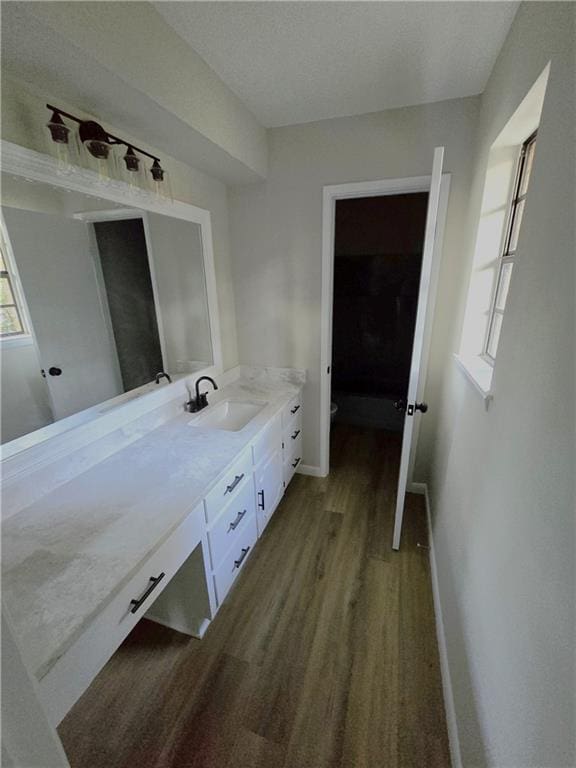 bathroom featuring baseboards, vanity, toilet, and wood finished floors