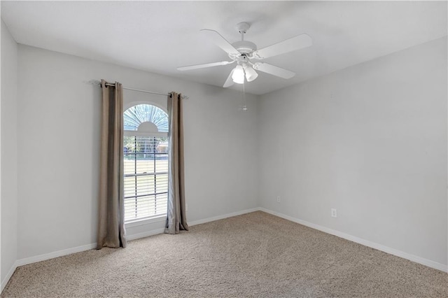 carpeted spare room with baseboards and a ceiling fan