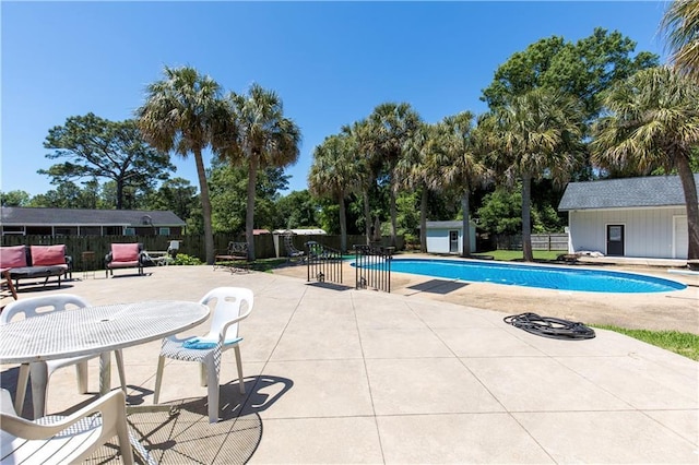 view of swimming pool featuring fence, a patio, a fenced in pool, and an outbuilding