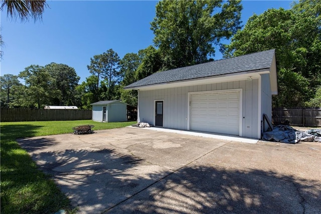 detached garage featuring driveway, a shed, and fence