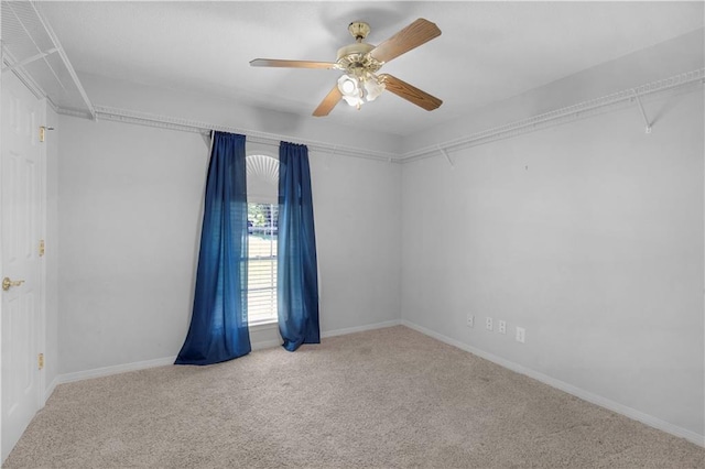 carpeted empty room featuring a ceiling fan and baseboards