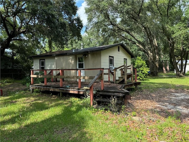 rear view of house with a wooden deck and a lawn