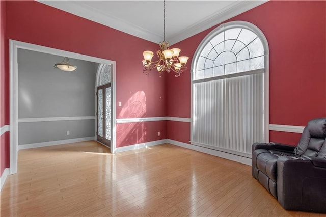 interior space featuring an inviting chandelier, ornamental molding, plenty of natural light, and light wood-type flooring