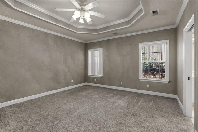 carpeted spare room featuring a raised ceiling, ornamental molding, and ceiling fan