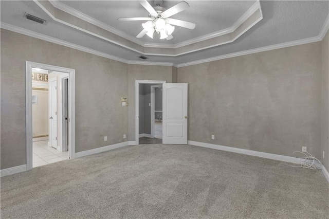 unfurnished bedroom with a raised ceiling, ornamental molding, and light colored carpet