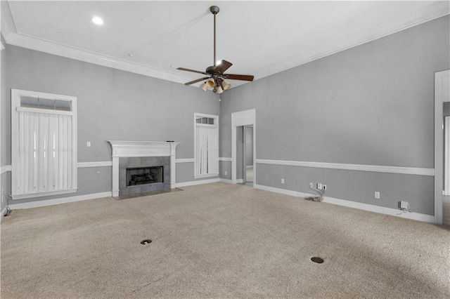 unfurnished living room with a tiled fireplace, crown molding, carpet, and ceiling fan