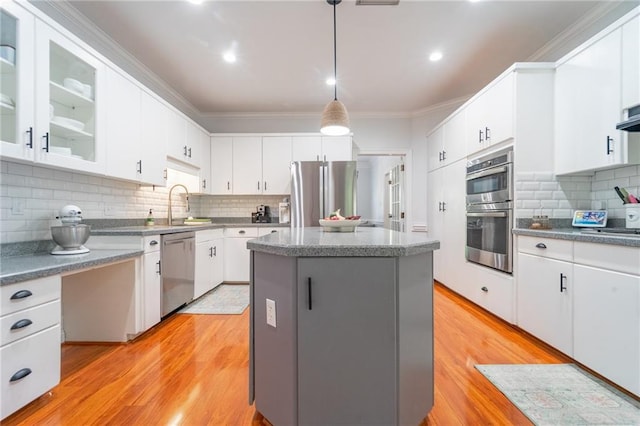 kitchen featuring tasteful backsplash, light wood-type flooring, a center island, appliances with stainless steel finishes, and a sink