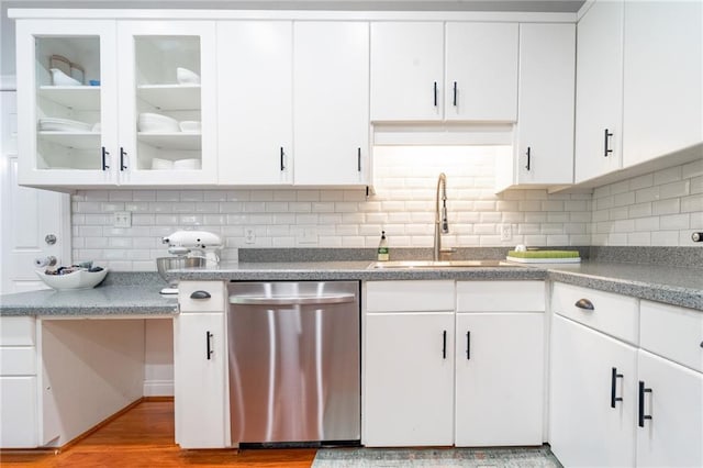 kitchen with glass insert cabinets, white cabinets, light wood-style floors, decorative backsplash, and dishwasher