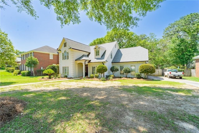 view of front of house featuring a front yard, roof with shingles, driveway, and fence