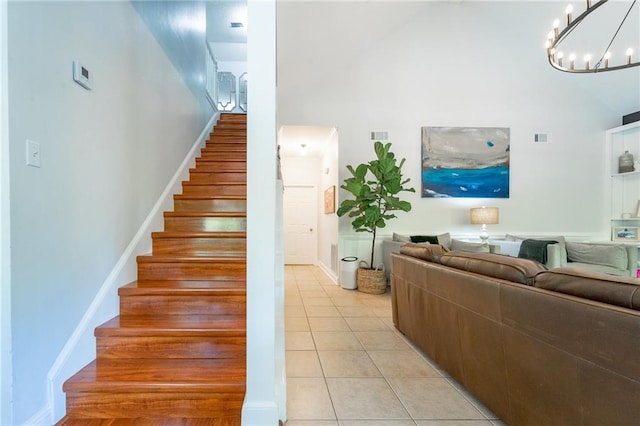 stairway with visible vents, baseboards, a notable chandelier, tile patterned floors, and high vaulted ceiling