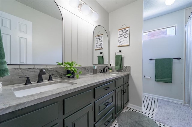 bathroom featuring double vanity, baseboards, and a sink