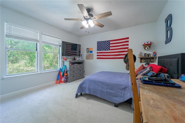 carpeted bedroom with a textured ceiling, baseboards, and a ceiling fan