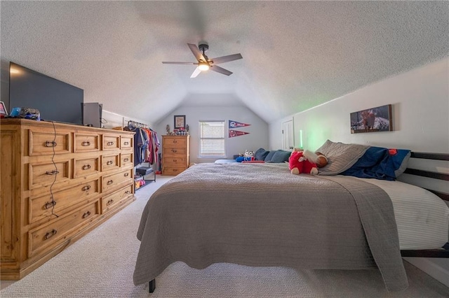 bedroom featuring ceiling fan, carpet flooring, vaulted ceiling, and a textured ceiling