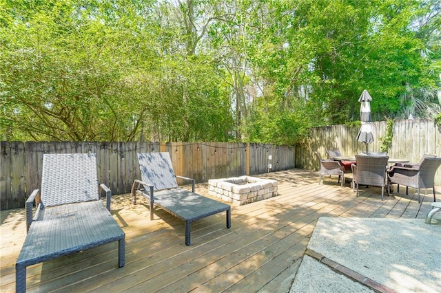 deck with a fenced backyard, an outdoor fire pit, and outdoor dining area