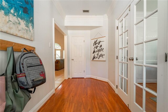 hallway with ornamental molding, visible vents, wood finished floors, french doors, and baseboards