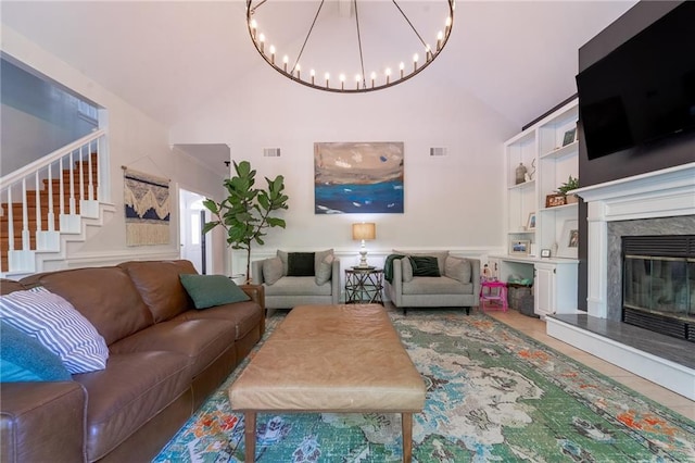 living area with visible vents, high vaulted ceiling, an inviting chandelier, and stairway