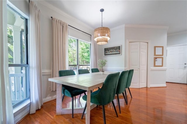 dining area with an inviting chandelier, ornamental molding, and wood finished floors
