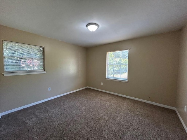 spare room with baseboards and carpet floors