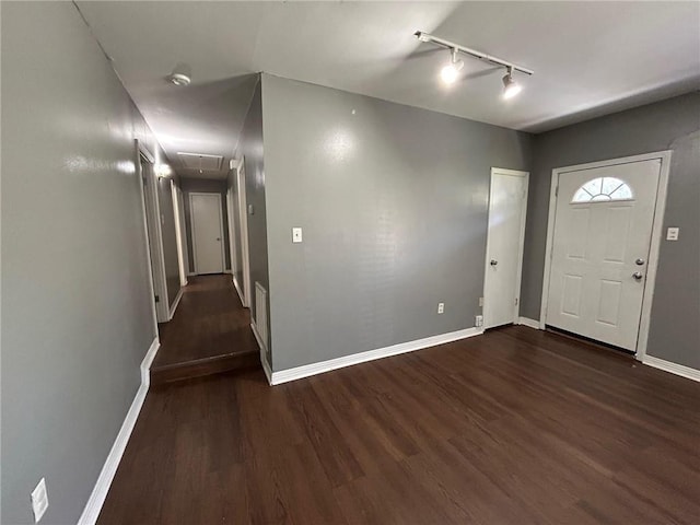 foyer entrance featuring rail lighting, dark wood-type flooring, baseboards, and visible vents