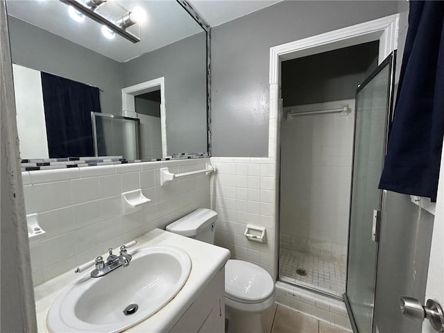 full bathroom featuring a stall shower, tile walls, vanity, and toilet