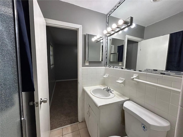 half bathroom with tile patterned flooring, tile walls, toilet, and vanity