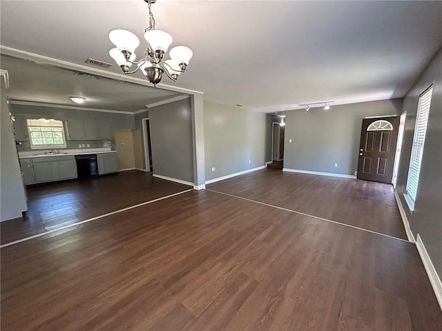 unfurnished living room with a sink, a notable chandelier, visible vents, baseboards, and dark wood-style floors