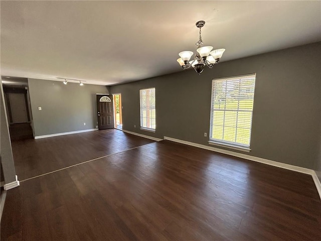 interior space featuring baseboards, a healthy amount of sunlight, and an inviting chandelier