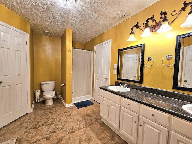 bathroom with a textured ceiling, vanity, and toilet