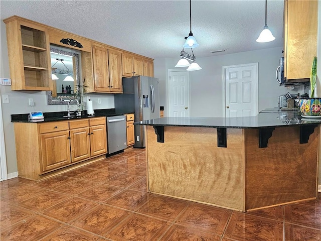 kitchen with pendant lighting, sink, kitchen peninsula, appliances with stainless steel finishes, and a kitchen breakfast bar