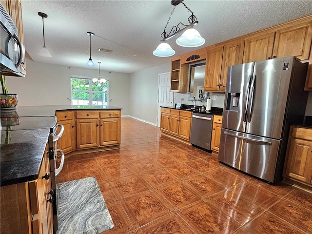 kitchen with appliances with stainless steel finishes, a textured ceiling, a chandelier, and decorative light fixtures