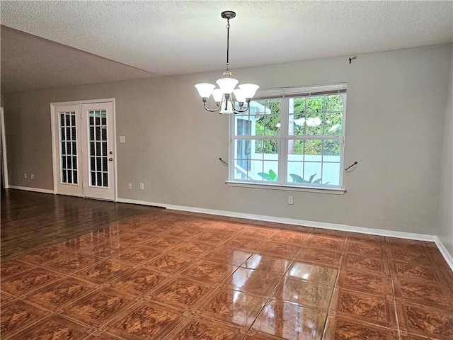 empty room featuring an inviting chandelier, a textured ceiling, and vaulted ceiling