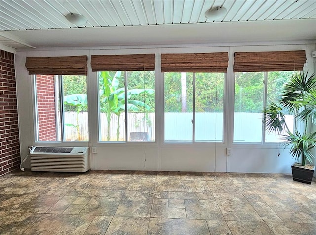 unfurnished sunroom with plenty of natural light and a wall mounted air conditioner