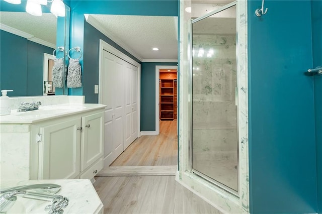 bathroom with a textured ceiling, hardwood / wood-style flooring, an enclosed shower, and crown molding