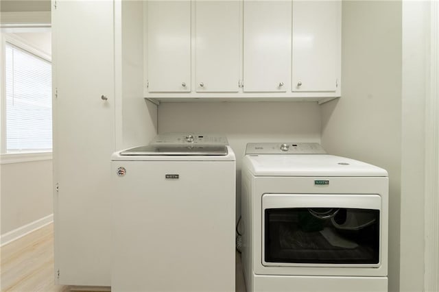 washroom featuring cabinets, separate washer and dryer, and light hardwood / wood-style floors