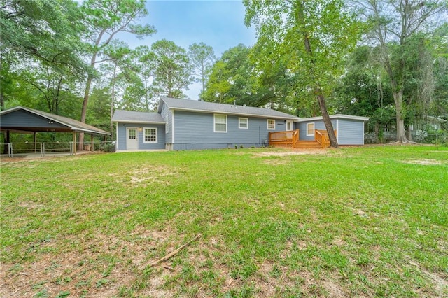 back of house with a carport, a wooden deck, and a lawn