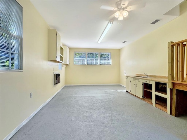 unfurnished living room featuring ceiling fan, sink, light carpet, and heating unit