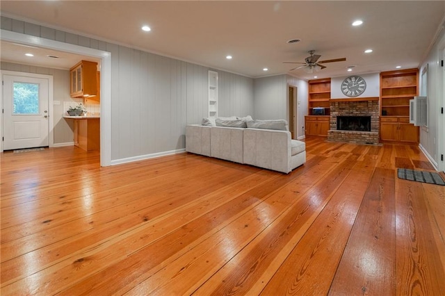 unfurnished living room with light hardwood / wood-style floors, a brick fireplace, ceiling fan, and ornamental molding