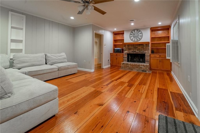 living room with a fireplace, light hardwood / wood-style flooring, built in features, and ornamental molding